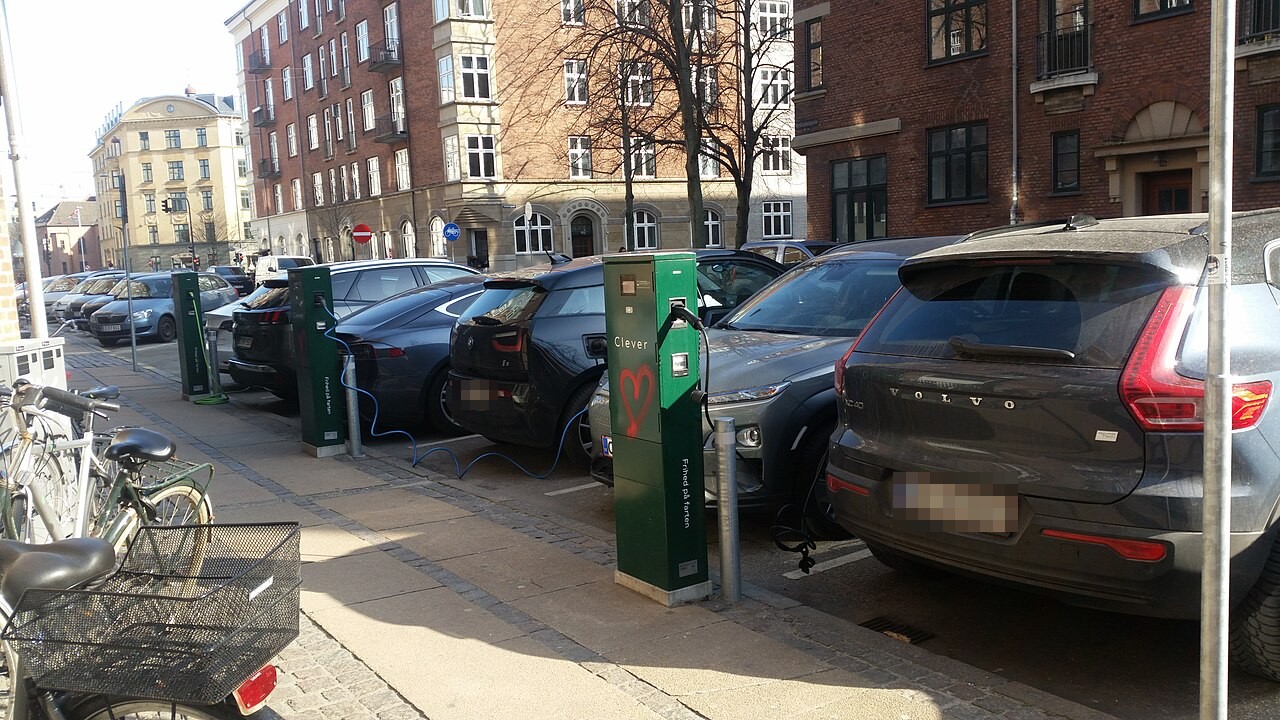 Elbiler holder til opladning ved grønne ladestandere langs et fortov på Vordingborggade på Østerbro i København