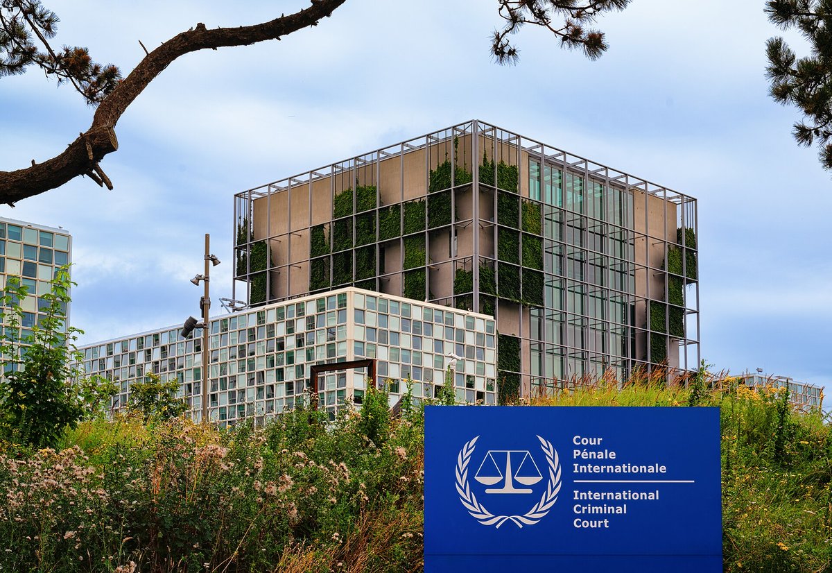 Den Internationale Straffedomstols bygning i Haag med et blåt skilt foran, hvor der står Cour Pénale Internationale og International Criminal Court