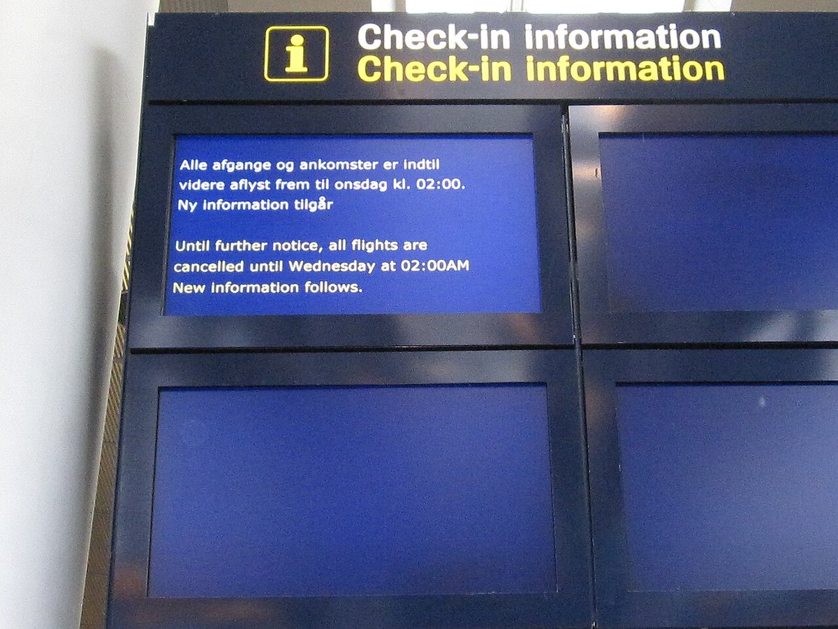 Informationsskærm i Københavns Lufthavn med teksten "Alle afgange og ankomster er indtil videre aflyst frem til onsdag kl. 02:00" på dansk og engelsk