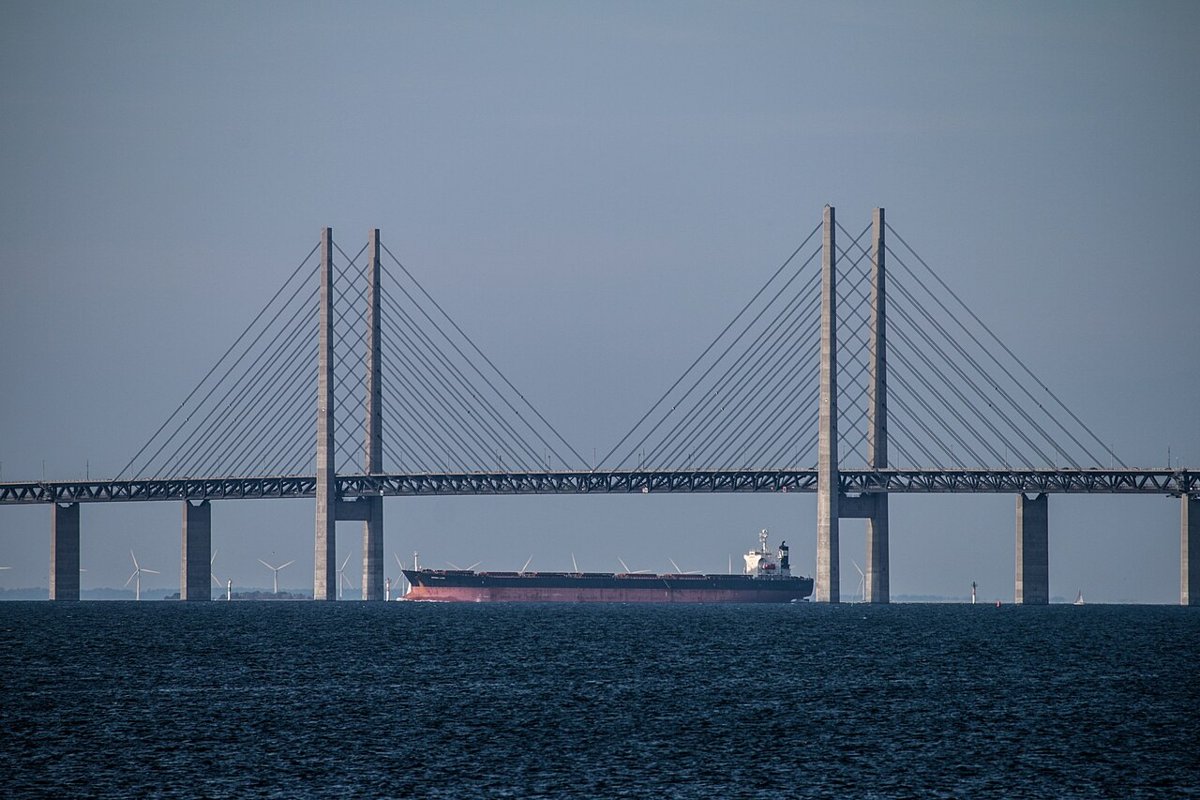 Et stort handelsskib passerer under Øresundsbroen med vindmøller i baggrunden