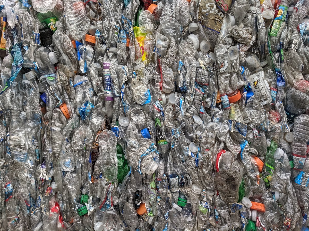 Tæt sammenpressede, brugte plastflasker med farvede låg og etiketter i en balle på et genanvendelsesanlæg