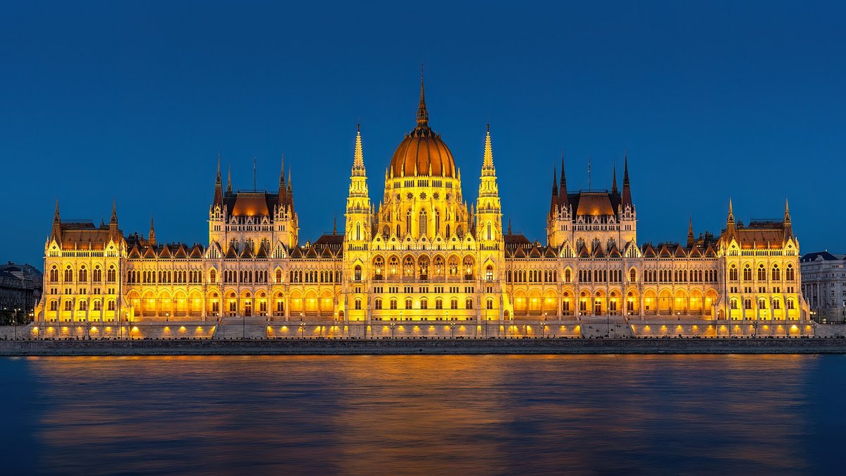 Det ungarske parlament i Budapest oplyst i aftenmørke, spejlet i Donau