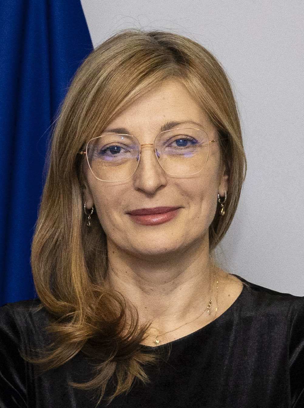 EU-kommissær Ekaterina Zaharieva med briller foran et blåt EU-flag
